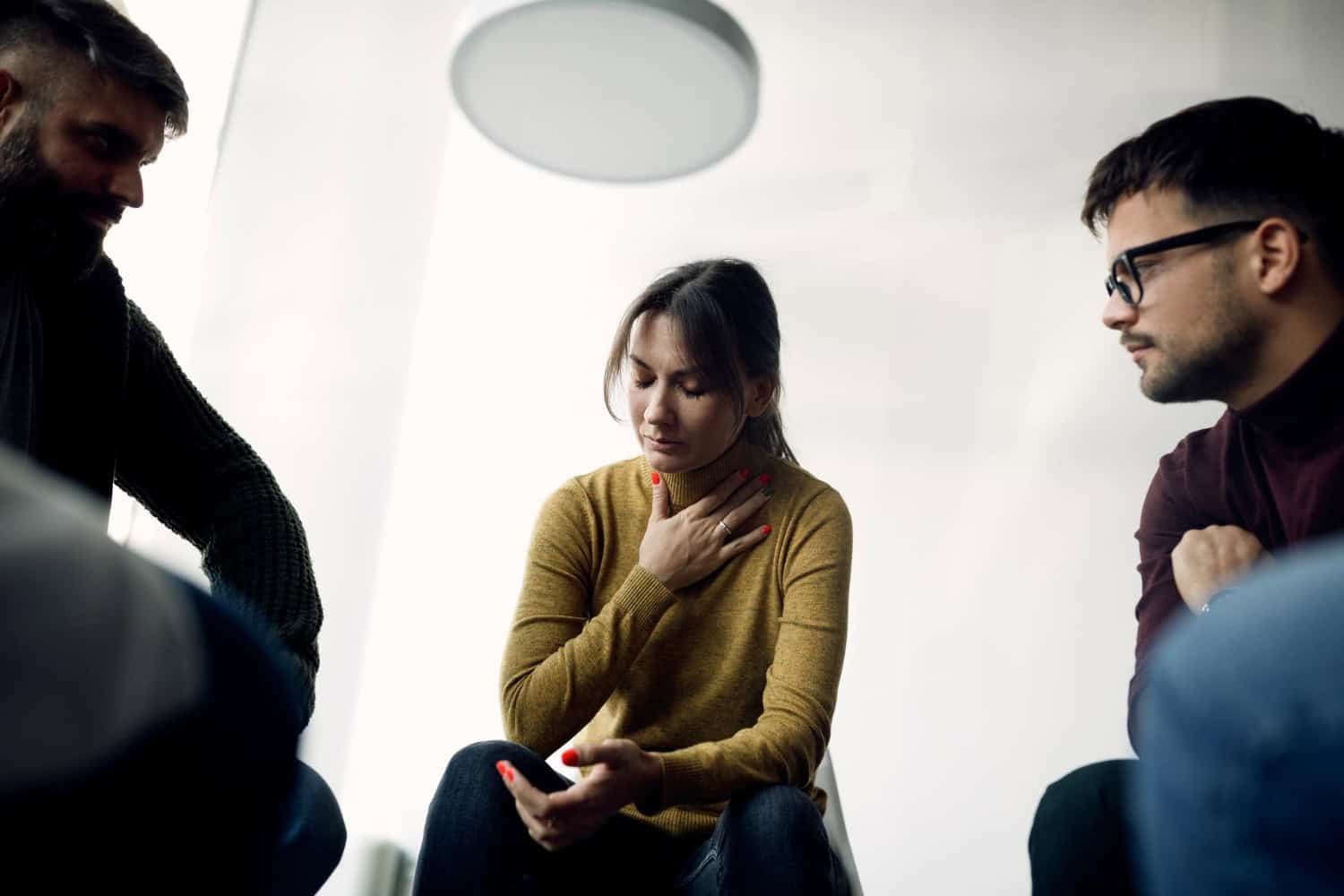 Depressed woman sharing her problems with members of group therapy