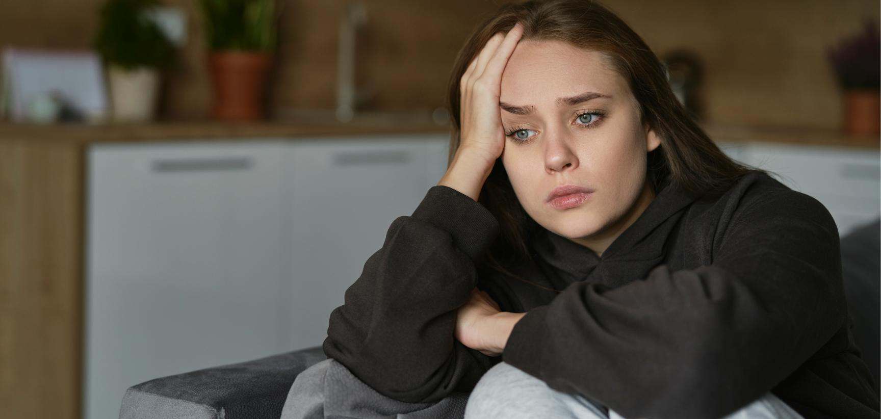 Individual seated on a couch appearing overwhelmed.