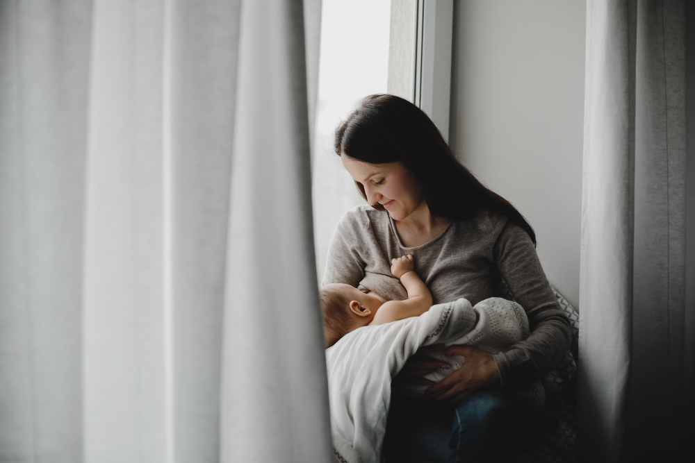 Mother holding and feeding her newborn while learning how to know if you have postpartum depression.